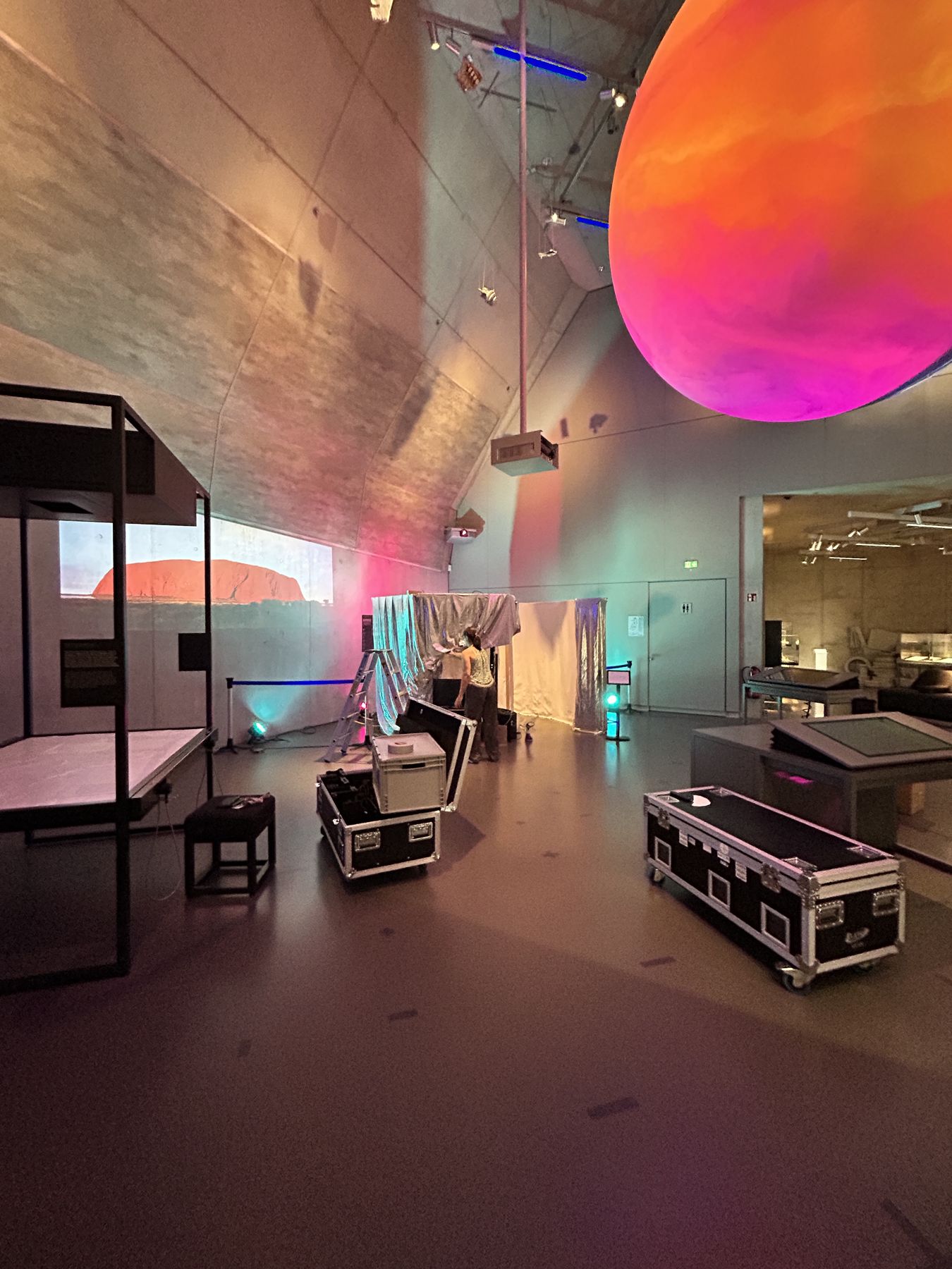 Aufbau im Museum: Flightcases, Leiter und die halb verhüllte Kabine unter einer leuchtenden Kugel.