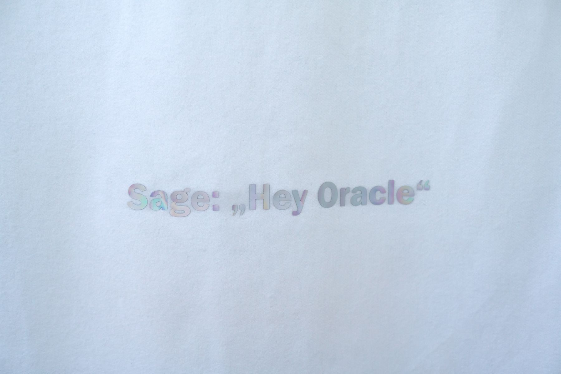 Holografische Schrift auf weißem Stoff: Sage: „Hey Oracle“.
